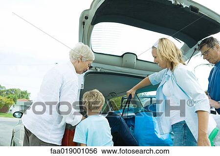 Stock Photograph - Family unloading trunk of car. Fotosearch