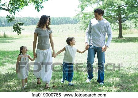 Family walking across grass, holding hands, front view View Large Photo Image Stock Photography - Family walking across grass, holding hands, front view. Fotosearch
