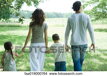 Picture - Family walking across grass, rear view. Fotosearch