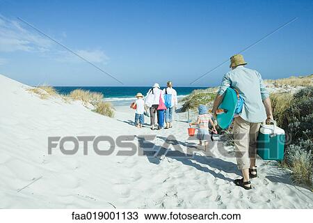 Stock Image - Family walking through dunes to beach. Fotosearch