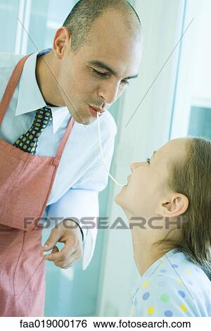 Stock Photograph - Father and daughter sharing spaghetti noodle. Fotosearch