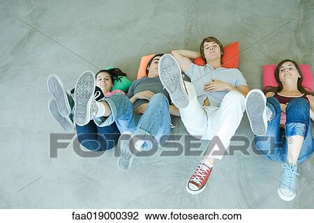 Four teen friends lying on backs on floor, holding up legs, focus on soles of shoes View Large Photo Image Stock Image - Four teen friends lying on backs on floor, holding up legs, focus on soles of shoes. Fotosearch
