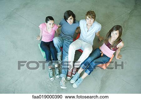 Four teen friends sitting on cushions on ground, looking at camera, high angle view View Large Photo Image Stock Image - Four teen friends sitting on cushions on ground, looking at camera, high angle view. Fotosearch