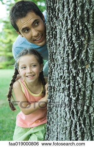 Girl and father peeking around tree View Large Photo Image Stock Photograph - Girl and father peeking around tree. Fotosearch