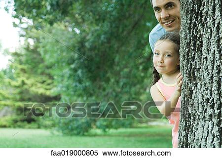 Girl and father peeking around tree View Large Photo Image Stock Photography - Girl and father peeking around tree. Fotosearch
