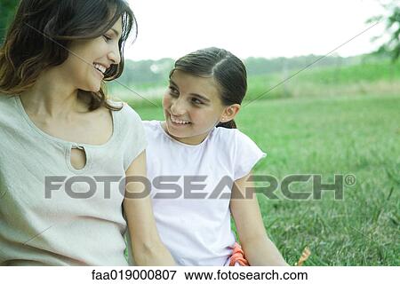 Girl and mother sitting outside, smiling at each other View Large Photo Image Stock Photo - Girl and mother sitting outside, smiling at each other. Fotosearch