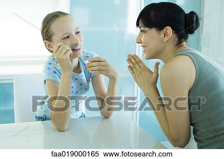 Girl eating ice cream dessert, woman looking at girl with hands clasped View Large Photo Image Stock Photography - Girl eating ice cream dessert, woman looking at girl with hands clasped. Fotosearch