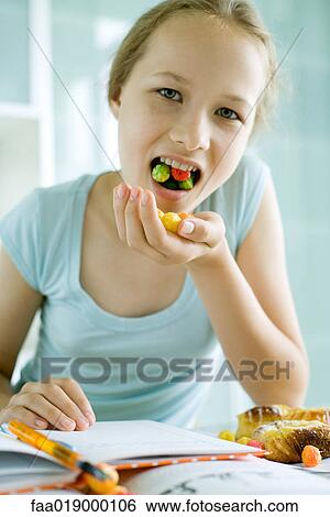 Girl eating sweets and doing homework View Large Photo Image Stock Photograph - Girl eating sweets and doing homework. Fotosearch