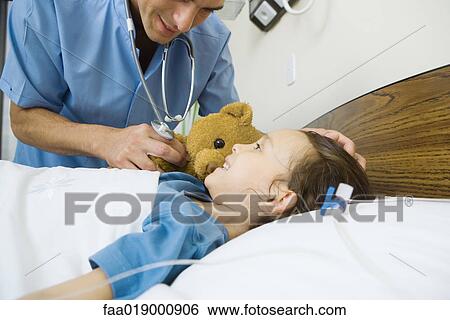 Stock Photograph - Girl lying in hospital bed, smiling at male nurse. Fotosearch