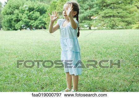 Girl reaching for bubbles View Large Photo Image Stock Photo - Girl reaching for bubbles. Fotosearch