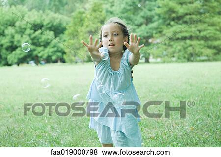 Girl reaching for bubbles View Large Photo Image Stock Photo - Girl reaching for bubbles. Fotosearch