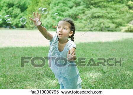 Stock Photography - Girl reaching for bubbles. Fotosearch