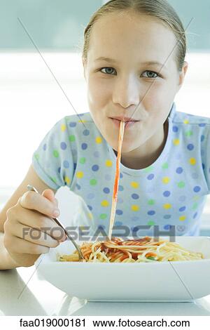 Stock Image - Girl slurping spaghetti noodles. Fotosearch