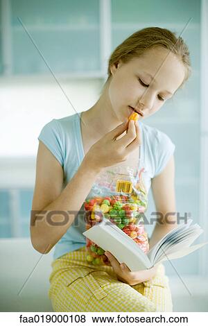 Girl snacking and reading View Large Photo Image Stock Photo - Girl snacking and reading. Fotosearch