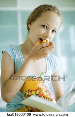 Stock Photo - Girl snacking and reading. Fotosearch