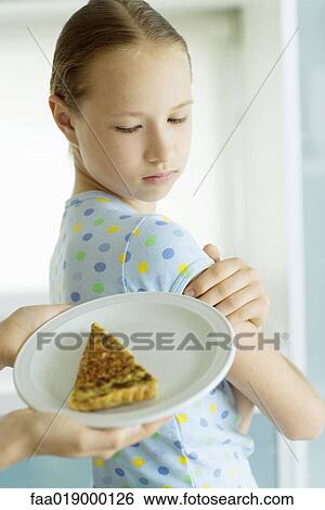 Stock Photograph - Girl turning away from hands holding plate of quiche. Fotosearch