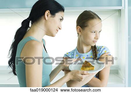 Girl turning head from woman holding piece of quiche View Large Photo Image Picture - Girl turning head from woman holding piece of quiche. Fotosearch