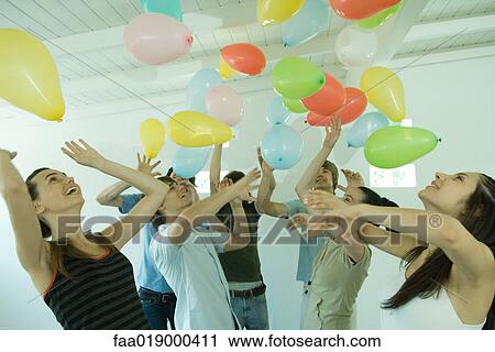 Group of young friends hitting balloons floating in the air View Large Photo Image Stock Image - Group of young friends hitting balloons floating in the air. Fotosearch
