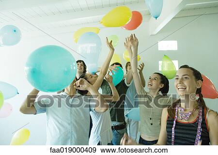 Group of young friends hitting balloons floating in the air View Large Photo Image Stock Photo - Group of young friends hitting balloons floating in the air. Fotosearch
