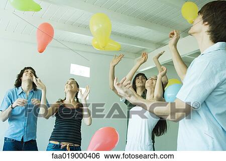 Group of young friends hitting balloons floating in the air View Large Photo Image Stock Photograph - Group of young friends hitting balloons floating in the air. Fotosearch