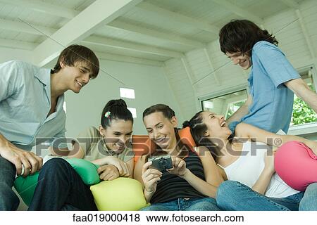 Stock Photo - Group of young friends sitting on sofa. Fotosearch