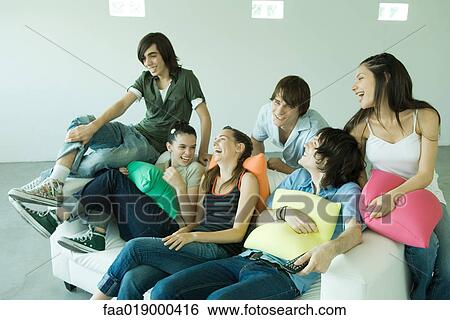 Group of young friends sitting on sofa, laughing View Large Photo Image Stock Photograph - Group of young friends sitting on sofa, laughing. Fotosearch