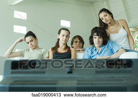 Stock Image - Group of young friends watching TV. Fotosearch