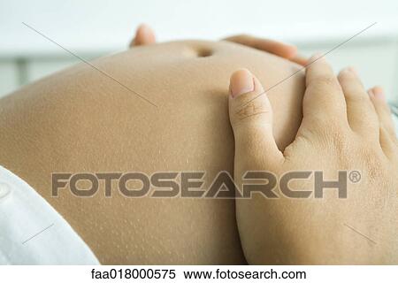 Stock Photography - Hands on pregnant stomach, close-up. Fotosearch