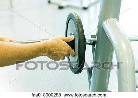 Man adjusting weight on barbell View Large Photo Image Stock Photo - Man adjusting weight on barbell. Fotosearch