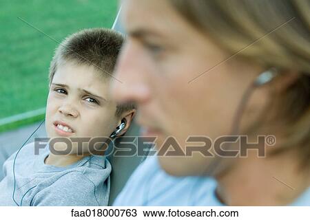 Man and boy listening to earphones together, focus on boy View Large Photo Image Stock Image - Man and boy listening to earphones together, focus on boy. Fotosearch