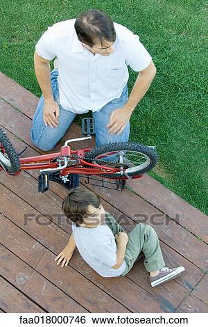 Stock Photograph - Man and boy working on bicycle. Fotosearch