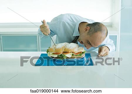 Man biting into large sandwich View Large Photo Image Picture - Man biting into large sandwich. Fotosearch