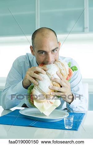 Man biting into large sandwich View Large Photo Image Stock Image - Man biting into large sandwich. Fotosearch