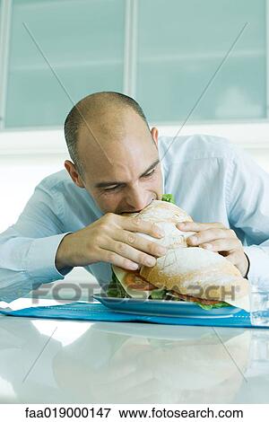 Stock Photo - Man biting into large sandwich. Fotosearch