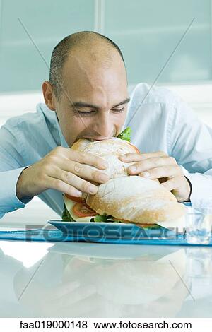 Man biting into large sandwich View Large Photo Image Stock Photo - Man biting into large sandwich. Fotosearch