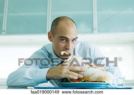 Stock Photo - Man biting into large sandwich. Fotosearch