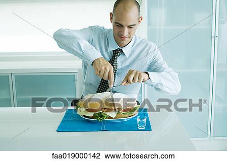 Man cutting into large sandwich with knife and fork View Large Photo Image Stock Image - Man cutting into large sandwich with knife and fork. Fotosearch