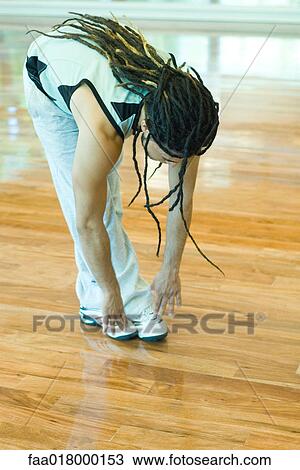 Stock Image - Man doing standing forward bend, full length. Fotosearch