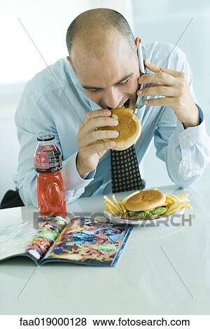 Man eating hamburgers, using cell phone, and looking at comic book View Large Photo Image Stock Photo - Man eating hamburgers, using cell phone, and looking at comic book. Fotosearch