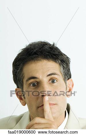 Stock Image - Man, finger over mouth, portrait. Fotosearch