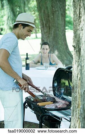 Man grilling meat on barbecue View Large Photo Image Stock Image - Man grilling meat on barbecue. Fotosearch
