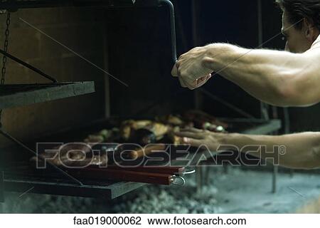 Man grilling meat on barbecue View Large Photo Image Stock Image - Man grilling meat on barbecue. Fotosearch