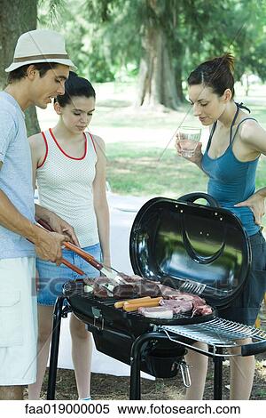 Man grilling meats on barbecue while woman and teen girl watch View Large Photo Image Stock Photography - Man grilling meats on barbecue while woman and teen girl watch. Fotosearch