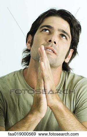 Stock Photo - Man hands together, looking up, portrait. Fotosearch