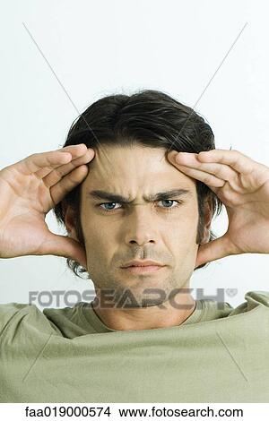 Picture - Man holding head, furrowing brow, portrait. Fotosearch