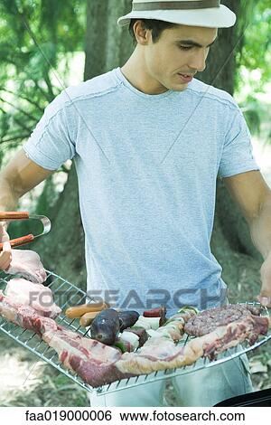 Man holding rack of meats to be grilled View Large Photo Image Stock Photograph - Man holding rack of meats to be grilled. Fotosearch