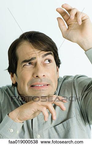 Stock Photo - Man holding up hands, looking up, portrait. Fotosearch