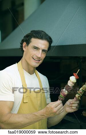 Man holding up kebabs View Large Photo Image Stock Photo - Man holding up kebabs. Fotosearch