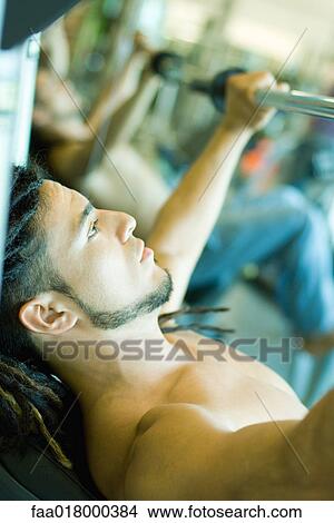 Man lifting barbell, side view View Large Photo Image Picture - Man lifting barbell, side view. Fotosearch