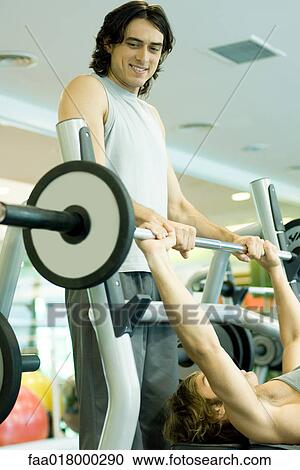 Man lifting barbell while second man spots View Large Photo Image Stock Image - Man lifting barbell while second man spots. Fotosearch